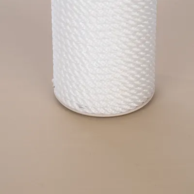 Bobine de corde blanche torsadée, matériau synthétique visible, présentée sur fond uni beige. Aucun texte ou marque apparente.
