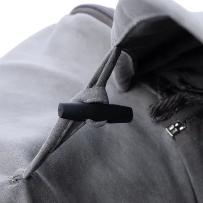 Close-up of a grey fabric strap with a black toggle fastener next to a zip. Suitable for adjusting or securing the product.