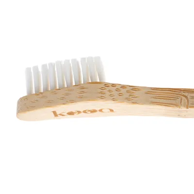 kooa zubná kefka z dreva s bielymi štetinami, ergonomicky tvarovaná rukoväť.