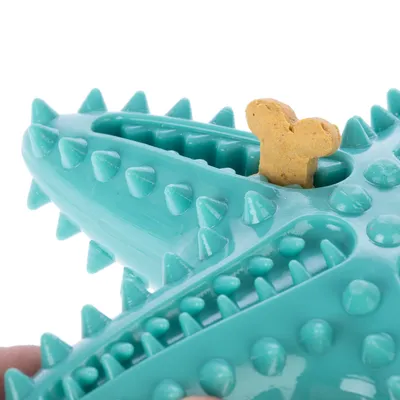 Tyrkysová hračka pre psa s výstupkami a otvorom, v ktorom je vložený keks v tvare kosti.