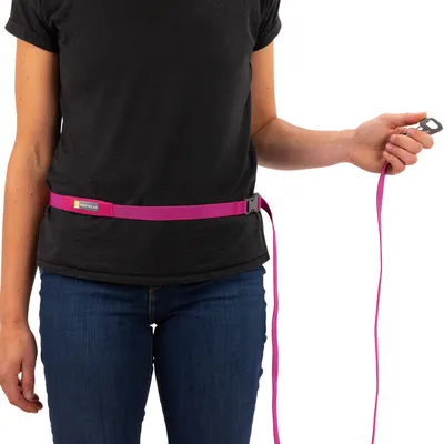 Person trägt einen pinken Ruffwear-Gürtel mit integrierter Leine, die in der Hand gehalten wird.