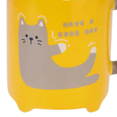 Texte en anglais sur la tasse : HAVE A GOOD DAY. Illustration d’un chat gris stylisé sur fond jaune.