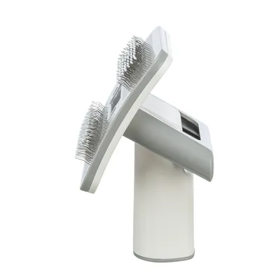Cepillo gris y blanco con cerdas metálicas finas, adecuado para el cuidado del pelaje. Diseño ergonómico con mango visible.