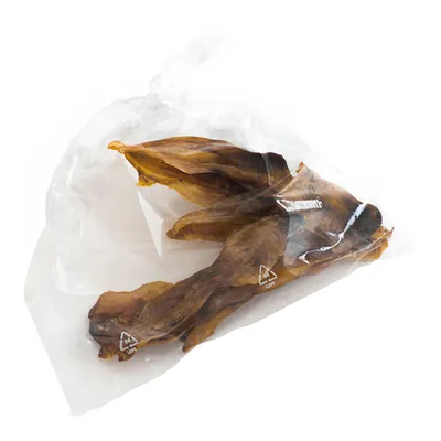 Gennemsigtig plastpose med flere brune tørrede godbidder synlige indeni. Genbrugssymbol LDPE trykt på posen.