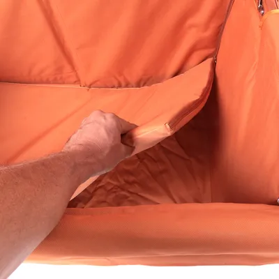 Hand hebt eine orangefarbene, gepolsterte Einlage in einem Produkt an, um die abnehmbare oder waschbare Funktion zu zeigen.
