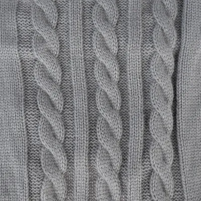 Gros plan sur un tricot torsadé gris, motif à mailles épaisses. Matière textile visible, type laine ou acrylique.