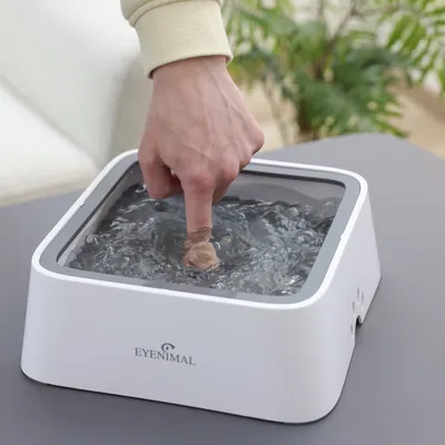 Eyenimal Trinkbrunnen mit Wasserbewegung, demonstriert durch Finger im Wasser.