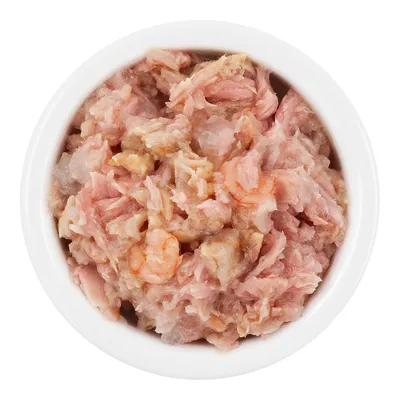 Primo piano di carne rosa e bianca tritata in una ciotola bianca. Ingredienti visibili: pezzi di gamberetti e carne di pesce.