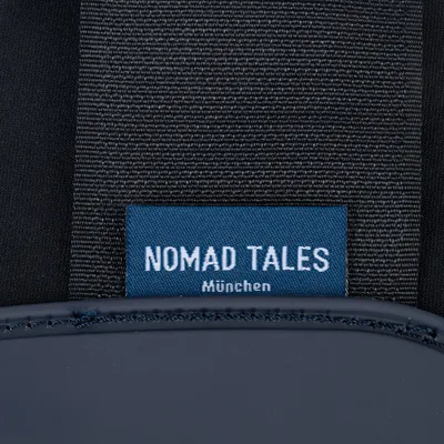 Nomad Tales München. Markenetikett auf dunkelgrauem Stoff.