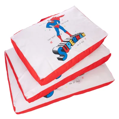 Coussins empilés avec illustration Superman, texte visible : SUPERMAN, super-speed, super-strength, man of steel. Bordures rouges, housse en tissu blanc.