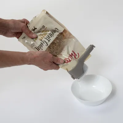 Roka drži odprto embalažo Ritzenhoff Weizenfrei Crunchy in vliva vsebino v belo skledo.
