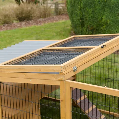 Recinto de madera con techo de rejilla metálica y cubierta de plexiglás, apto para exteriores. Bisagras y cierre visibles en el techo.