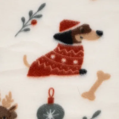 Primo piano di un motivo tessile con cane in maglione rosso, ossi, pallina di Natale e rametti decorativi. Primo piano di un motivo tessile con cane in maglione rosso, ossi, pallina di Natale e rametti decorativi.