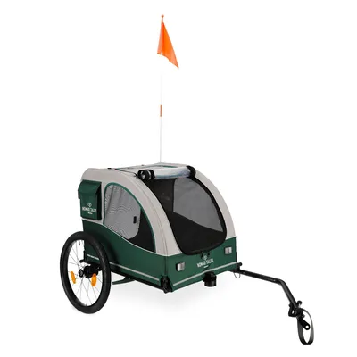 Grüner Fahrradanhänger mit zwei Rädern, Netzfenstern und orangefarbener Sicherheitsflagge. Marke: Nomad Tales.