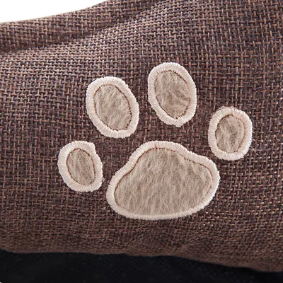 Bruine stof met geborduurde pootafdruk in beige pluche materiaal, detailopname van huisdieraccessoire. Materiaal: textiel en pluche.