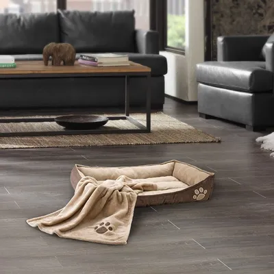 Hondenmand van beige stof met opstaande randen en een bijpassende deken, beide voorzien van pootafdrukmotief.