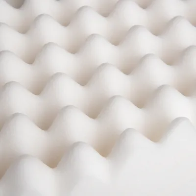 Nahaufnahme einer weissen Schaumstoffmatte mit wellenförmiger Struktur, geeignet für Polsterung oder Komfortzwecke.
