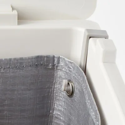 Detail van een witte kunststof container met grijze binnenzak van geweven kunststof, bevestigd met metalen oog en plastic knop.