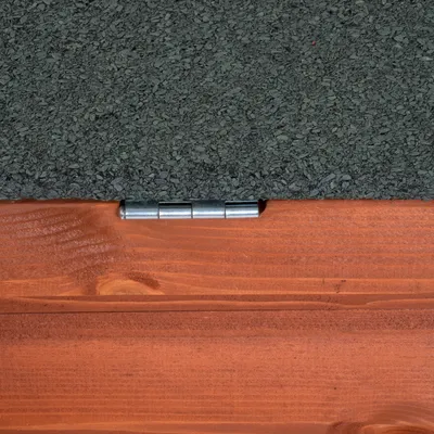 Detalle de bisagra metálica en estructura de madera con superficie superior rugosa de color gris oscuro. Detalle de bisagra metálica en estructura de madera con superficie superior rugosa de color gris oscuro.