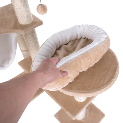 Krabpaal met beige pluche mandje, hand toont afneembaarheid van het mandje. Sisal krabpalen en hangend pluche balletje zichtbaar.