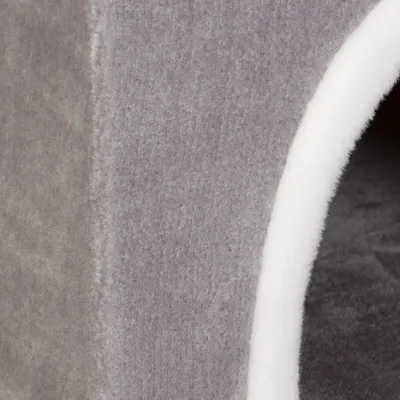 Detalle de superficie exterior e interior de una caseta para mascotas en tela gris con borde blanco visible en la entrada.