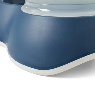 Close-up of a blue food bowl with white rim and integrated water container.