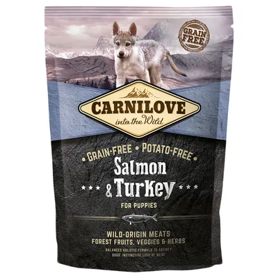 Confezione Carnilove into the Wild, Grain-Free, Potato-Free, Salmon & Turkey for Puppies. Testo visibile: Wild-Origin Meats, Forest Fruits, Veggies & Herbs. Immagine di un cucciolo.
