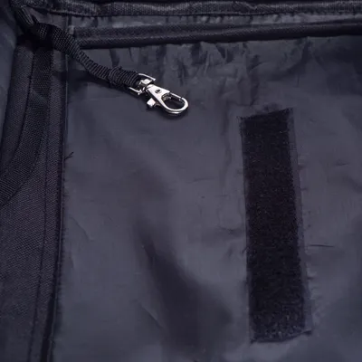 Intérieur en tissu noir avec sangle munie d’un mousqueton métallique et bande velcro visible, détails d’accessoire pour animal.