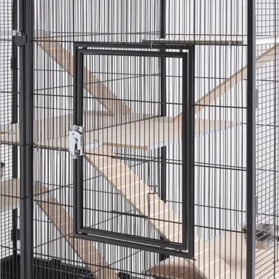 Grosser Metallkäfig mit mehreren Holzplattformen und Rampen, Tür mit Sicherheitsverschluss sichtbar.