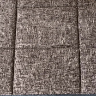 Nahaufnahme eines braunen, texturierten Stoffmaterials mit quadratischer Steppung.