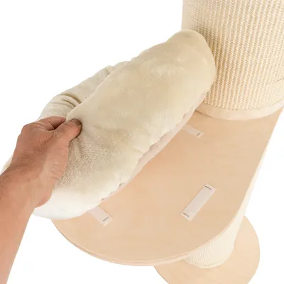Hand showing removable, beige padded cushion with hook-and-loop fastener on a wooden platform next to a sisal scratching post.