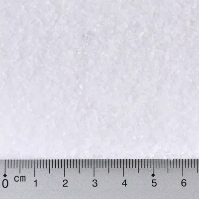 Gránulos blancos con regla métrica en centímetros debajo, mostrando el tamaño aproximado de los granos entre 0 y 6 cm.