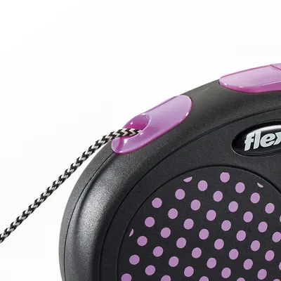 Guinzaglio avvolgibile Flexi con dettagli viola e corda bianca e nera, parte del marchio visibile sulla scocca nera a pois viola.