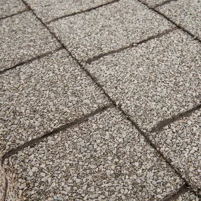 Close-up van grijze, gestructureerde vloertegels met kiezeloppervlak en voegen.