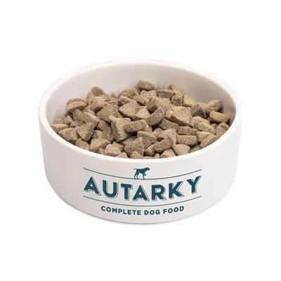 Bowl filled with Autarky complete dog food, showing the product's kibble pieces and the label 'Autarky Complete Dog Food' on the bowl.