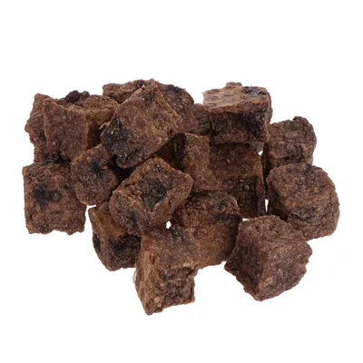 Morceaux de friandises brunes en forme de cubes, sans emballage ni marque visible, présentés en tas sur fond blanc.