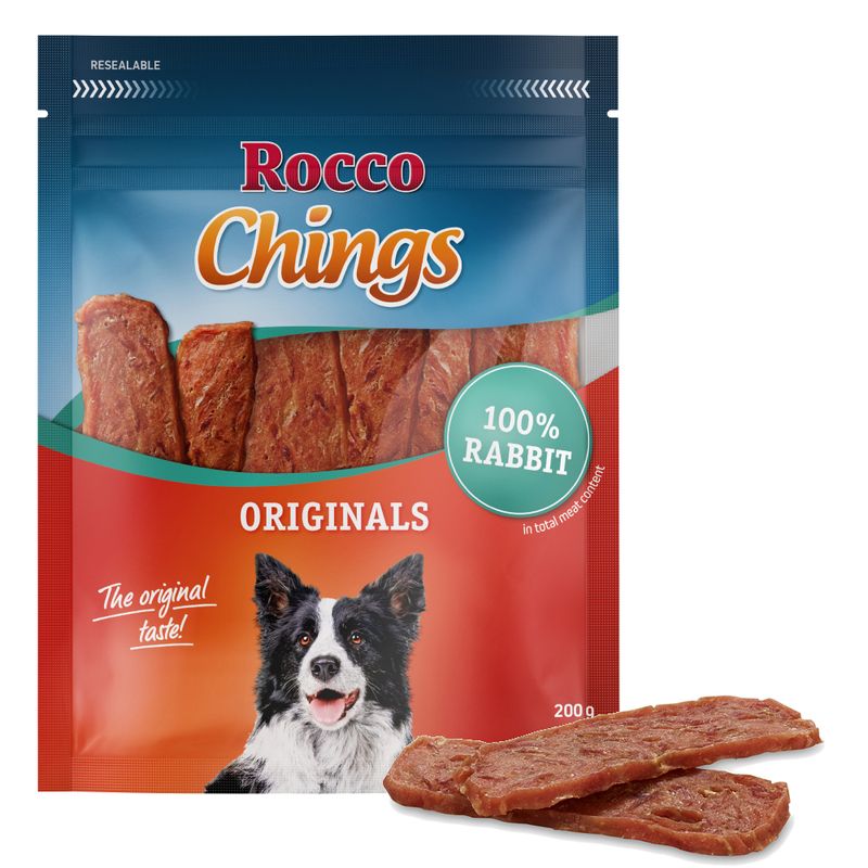 Упаковка лакомства для собак Rocco Chings Originals, 100% Rabbit, 200 г; изображены полоски мясного продукта и собака на упаковке. Видна надпись: The original taste!