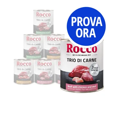 Rocco Trio di Carne, lattine con carne visibile e testo 'Beef with chicken and veal', '3 meat varieties'. Bollino blu con scritta 'PROVA ORA' in bianco.