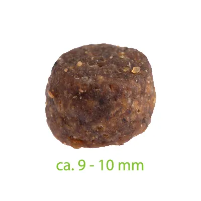 Nahaufnahme eines braunen Futterstücks mit einer Grösse von ca. 9-10 mm, Textangabe in grün.