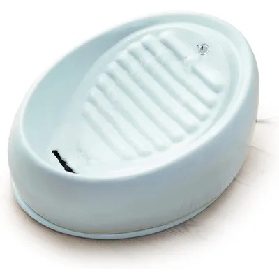 Fuente de agua eléctrica para mascotas de cerámica blanca, con superficie acanalada y chorro de agua visible en la parte superior.