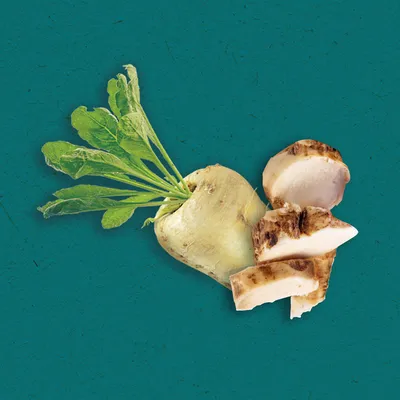 Cijela bijela repa s lišćem i nekoliko narezanih komada korijena na zelenoj podlozi