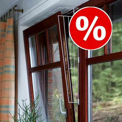 Rejilla de protección blanca instalada en ventana abatible de madera. Círculo rojo con símbolo de porcentaje blanco indica oferta o descuento.