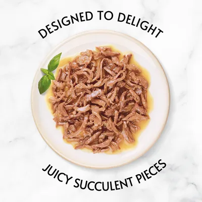 Tányéron szaftos, szálas húsdarabok, mellette bazsalikomlevél. Felirat angolul: DESIGNED TO DELIGHT, JUICY SUCCULENT PIECES.