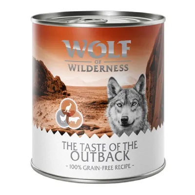 Conservă Wolf of Wilderness, inscripție: THE TASTE OF THE OUTBACK, 100% grain-free recipe. Imagine cu peisaj deșertic și siluete animale pe etichetă.