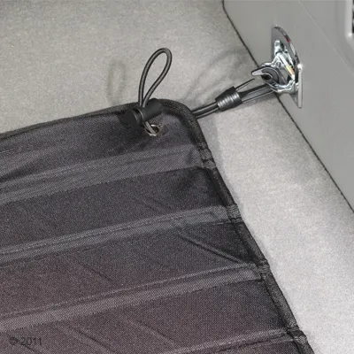 Black protective mat with fastening loop and clip, attached to a metal holder in the vehicle.