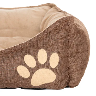 Ruskea lemmikkisänky, jossa beige tassukuvio sivussa, pehmustettu sisäpinta mukavuuden vuoksi.