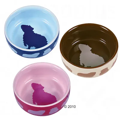 Tre ciotole per alimenti in blu, marrone e rosa con sagome di cani all'interno e motivi decorativi all'esterno.