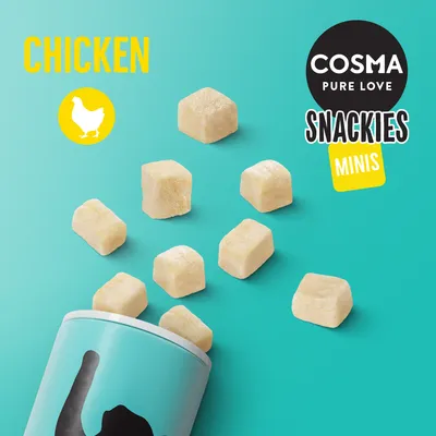 COSMA PURE LOVE SNACKIES MINIS CHICKEN. Billede af små lyse ternede godbidder, der hældes ud af en dåse med sort kattefigur. Teksten 'CHICKEN' og kyllingesymbol er synlige.