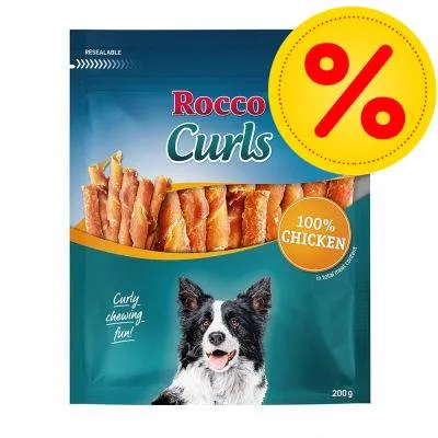 Balení Rocco Curls, 100% Chicken, 200 g. Na obalu je vyobrazen pes a žlutý symbol procenta v červeném kruhu. Balení Rocco Curls, 100% Chicken, 200 g. Na obalu je vyobrazen pes a žlutý symbol procenta v červeném kruhu.