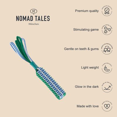 NOMAD TALES München. Texto en inglés: Premium quality, Stimulating game, Gentle on teeth & gums, Light weight, Glow in the dark, Made with love. Juguete de cuerda verde y azul.